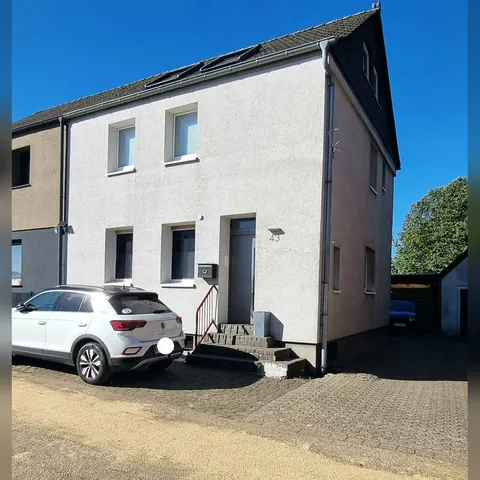 Doppelhaushälfte mit heller Fassade und Auffahrt